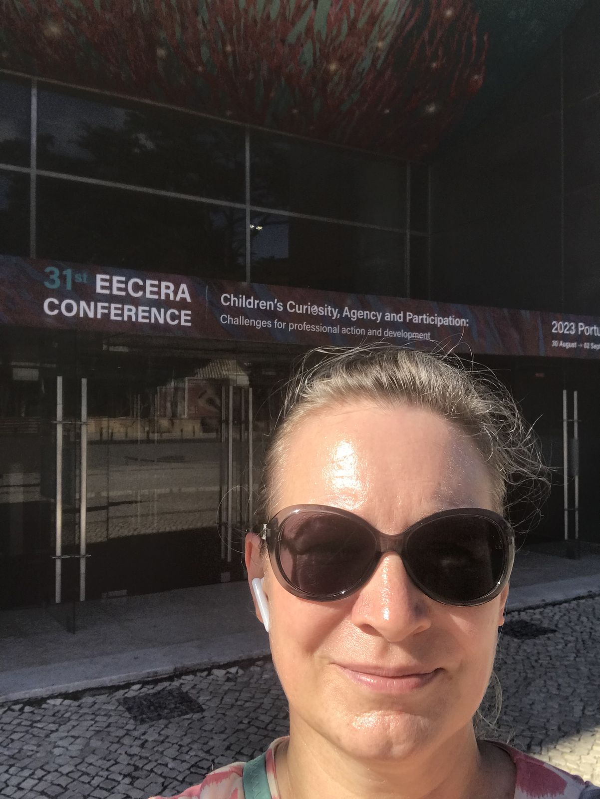 Selfie of a lady wearing sunglasses outside the doors of a conference centre