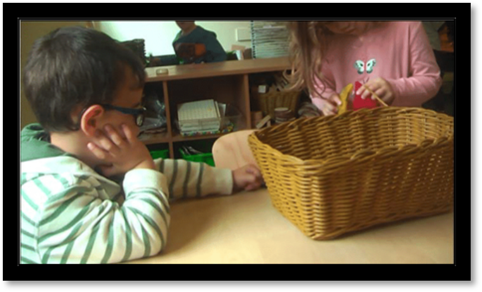 A boy is trying to play with a girl, he is offering her a Magnatile piece in an attempt to be included.