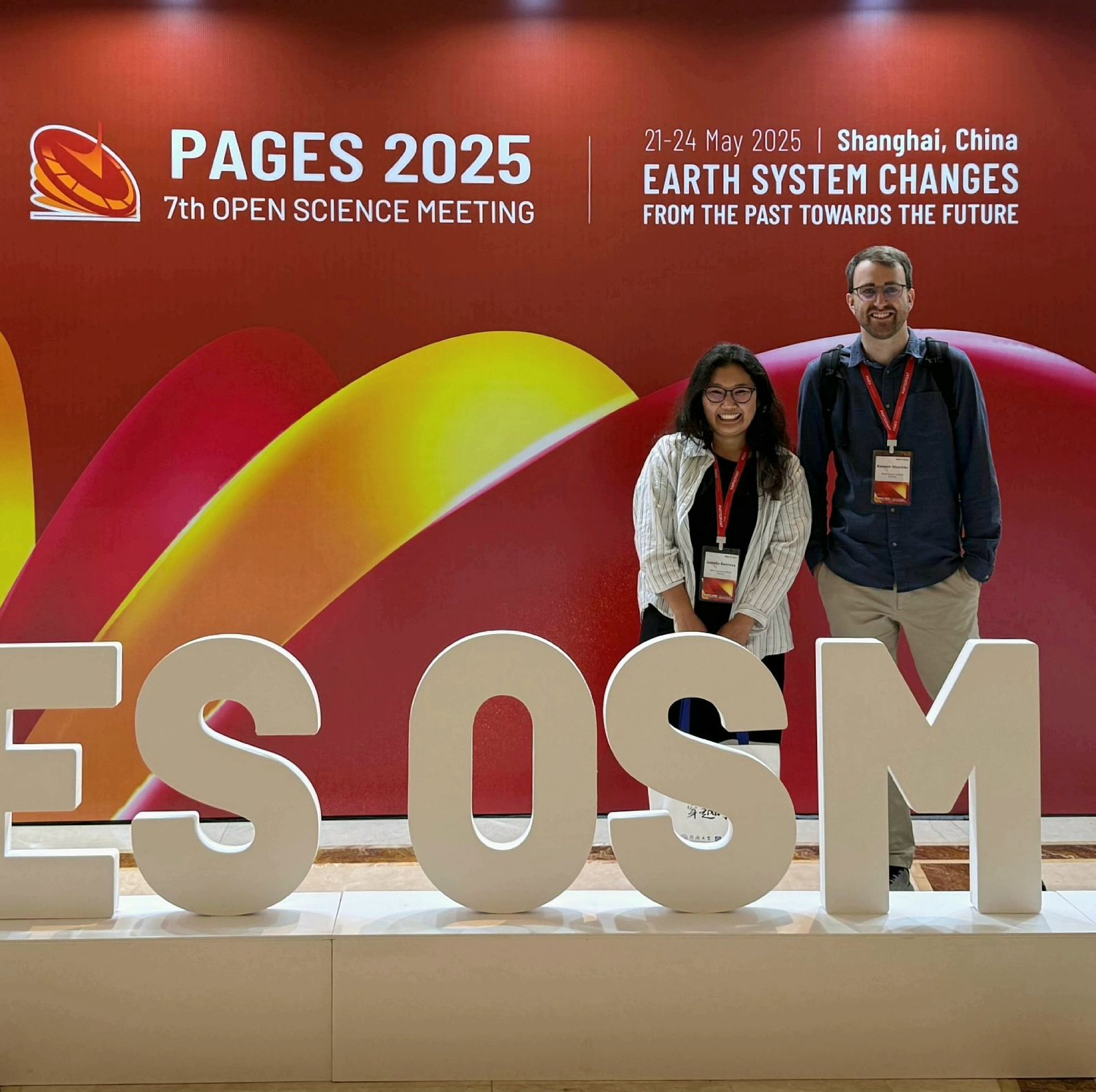 Two people standing in front of a large conference banner.