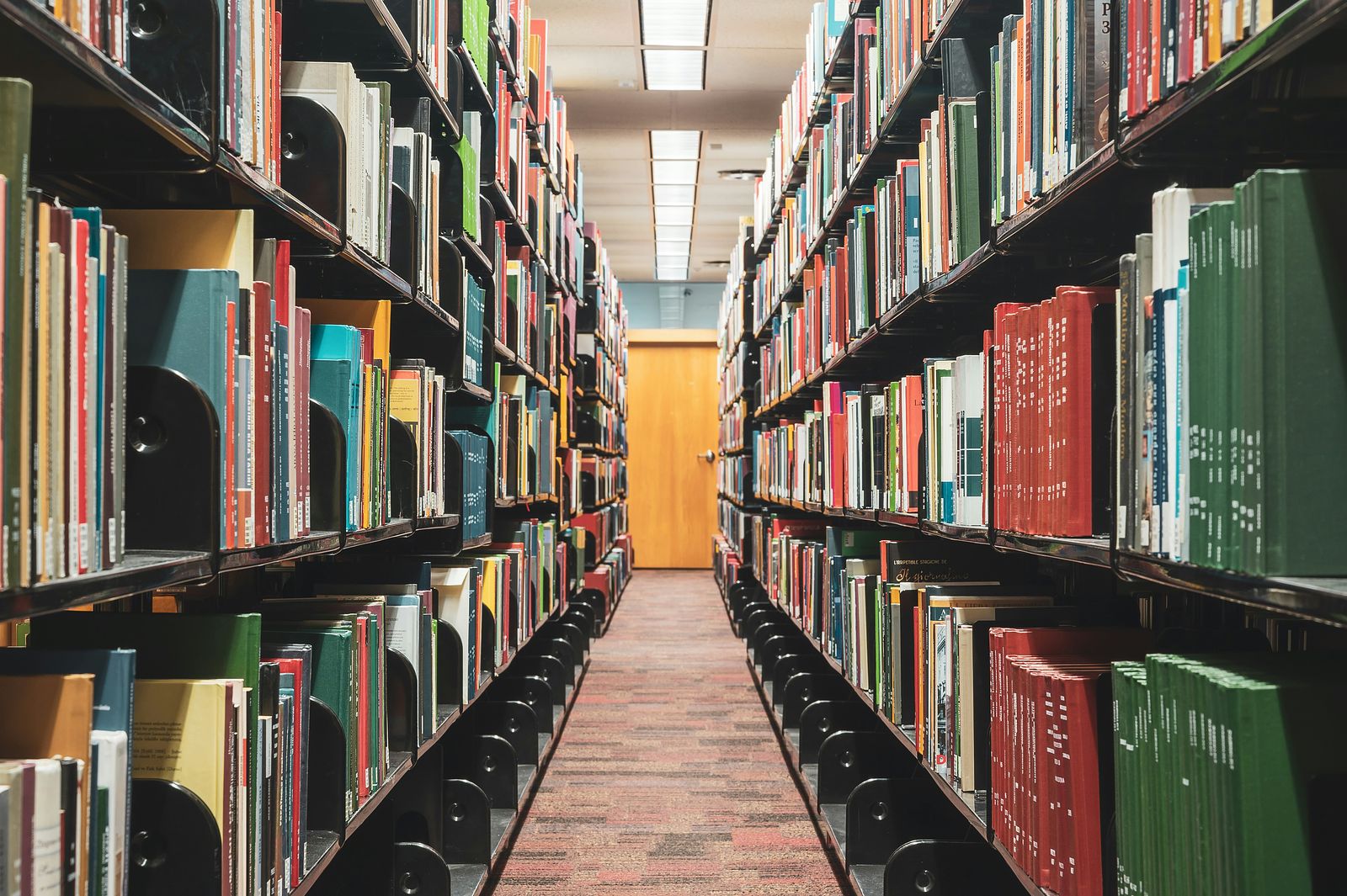 An aisle between shelves of books in a library.