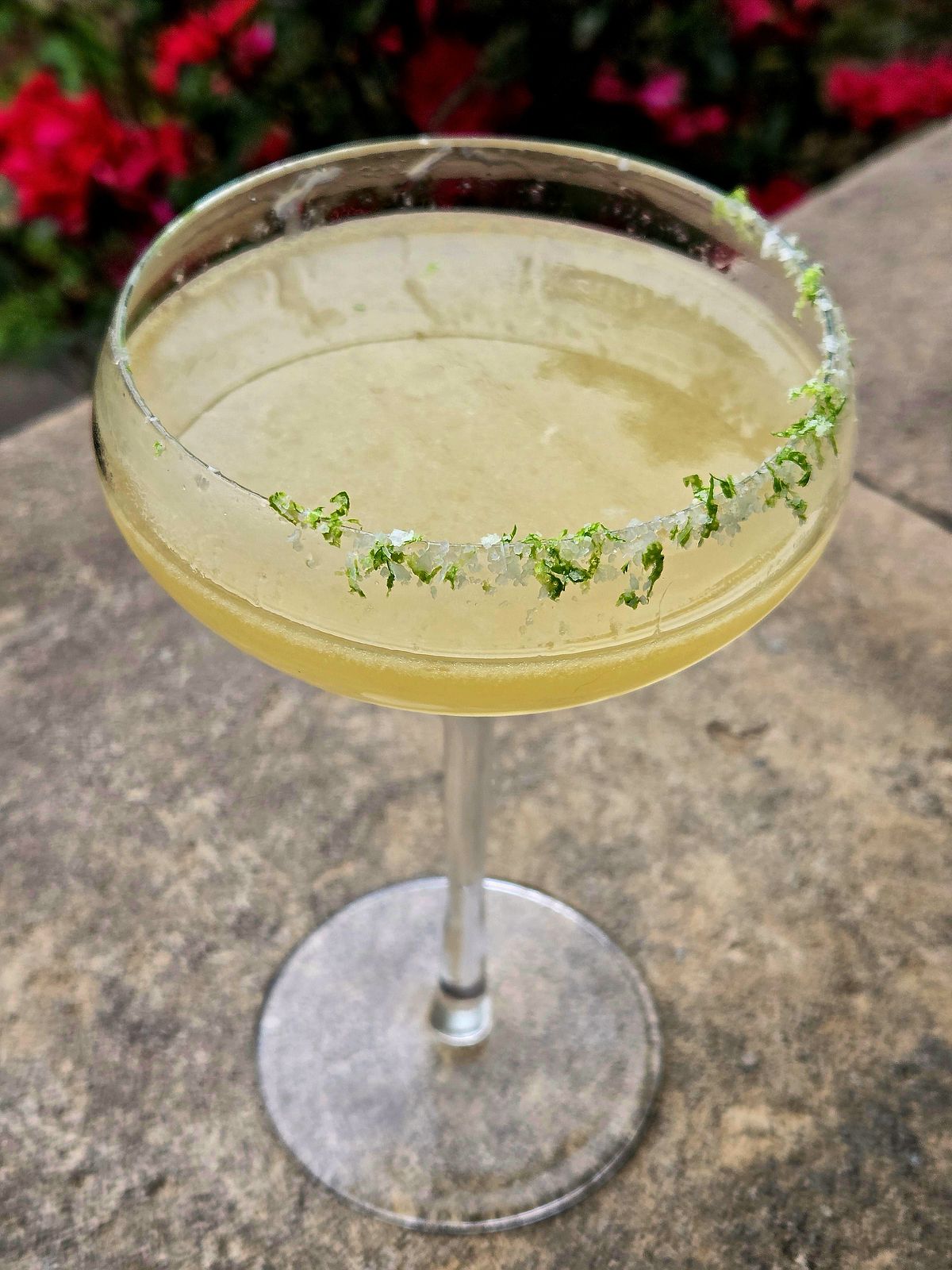 Coconut Margarita with Orange Curaçao and lime salt rim in a Coupe atop a stone wall.