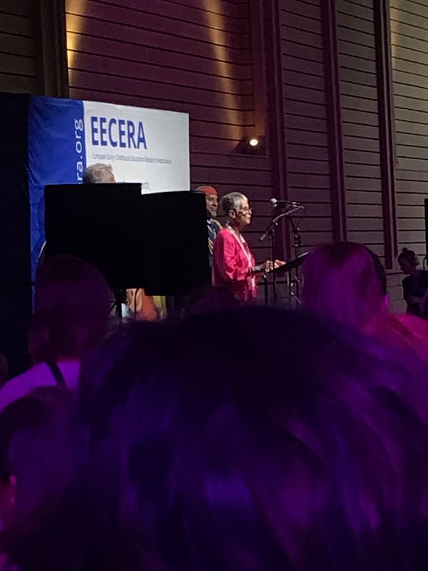 A woman is standing in front of a sign which says EECERA