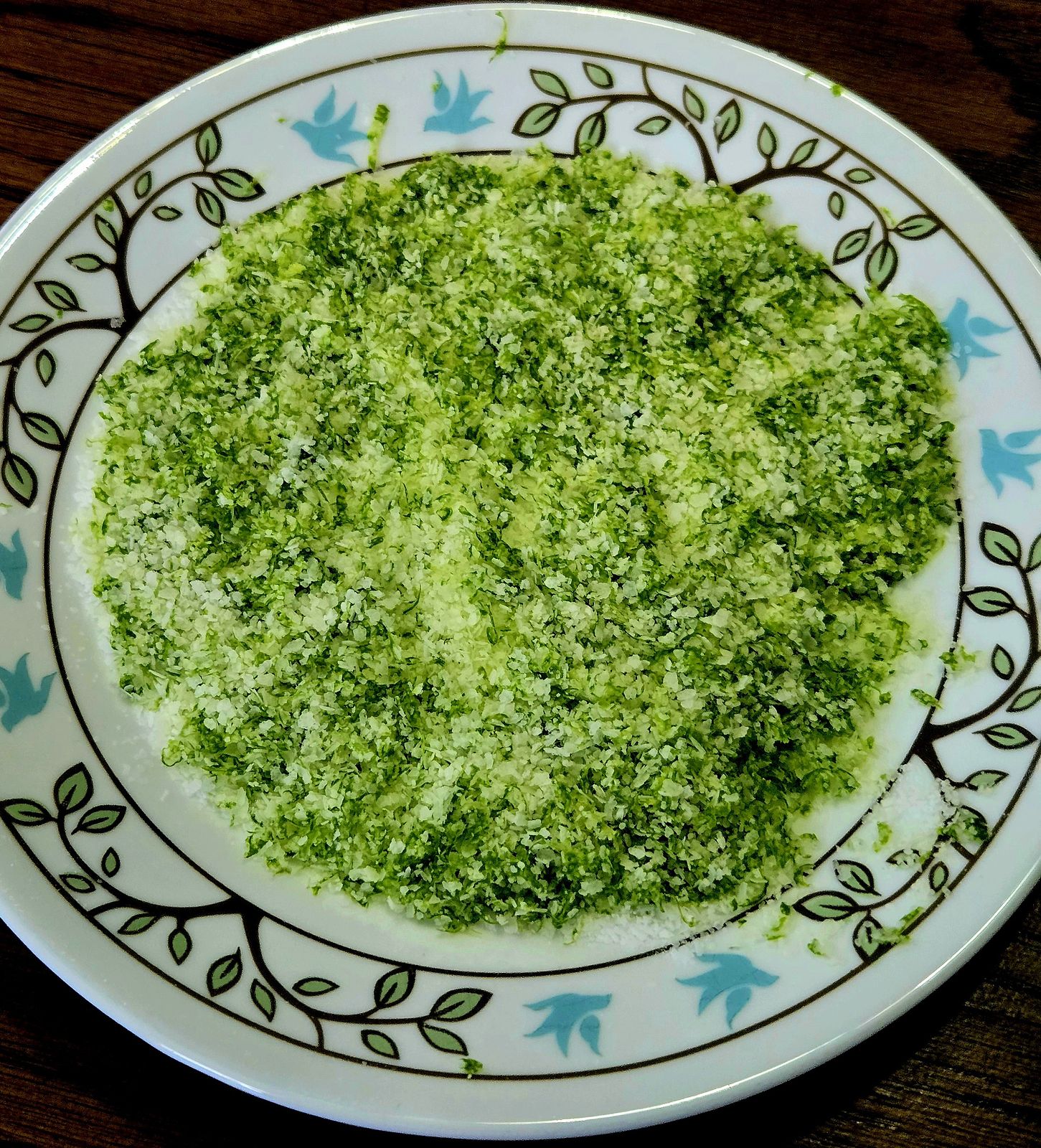 Lime salt in a tea saucer atop a wooden table.