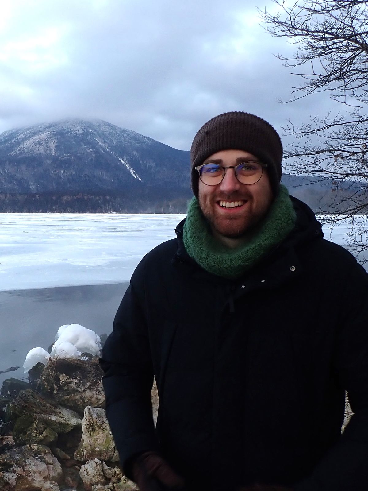 Me standing in front of a party frozen lake, with a volcano in the background.