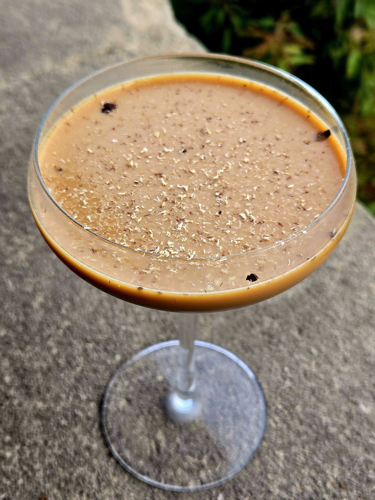 Mendoza Martini in a Coupe with grated Tonka bean garnish atop a stone wall.