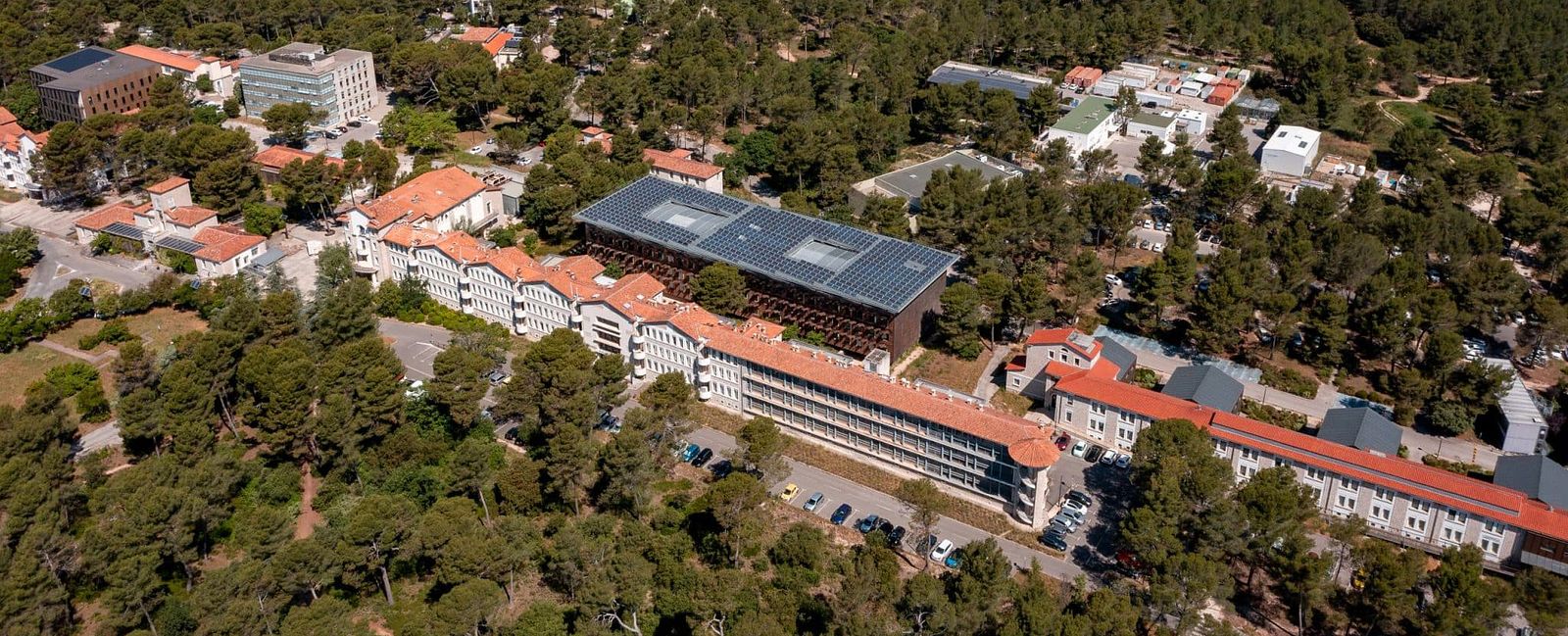 Aerial view taken by drone of the CEREGE, research center, based in plateau de l'Arbois, Aix-en-Provence, showing the historic white stone facade, surrounded by beautiful provençale pine forest