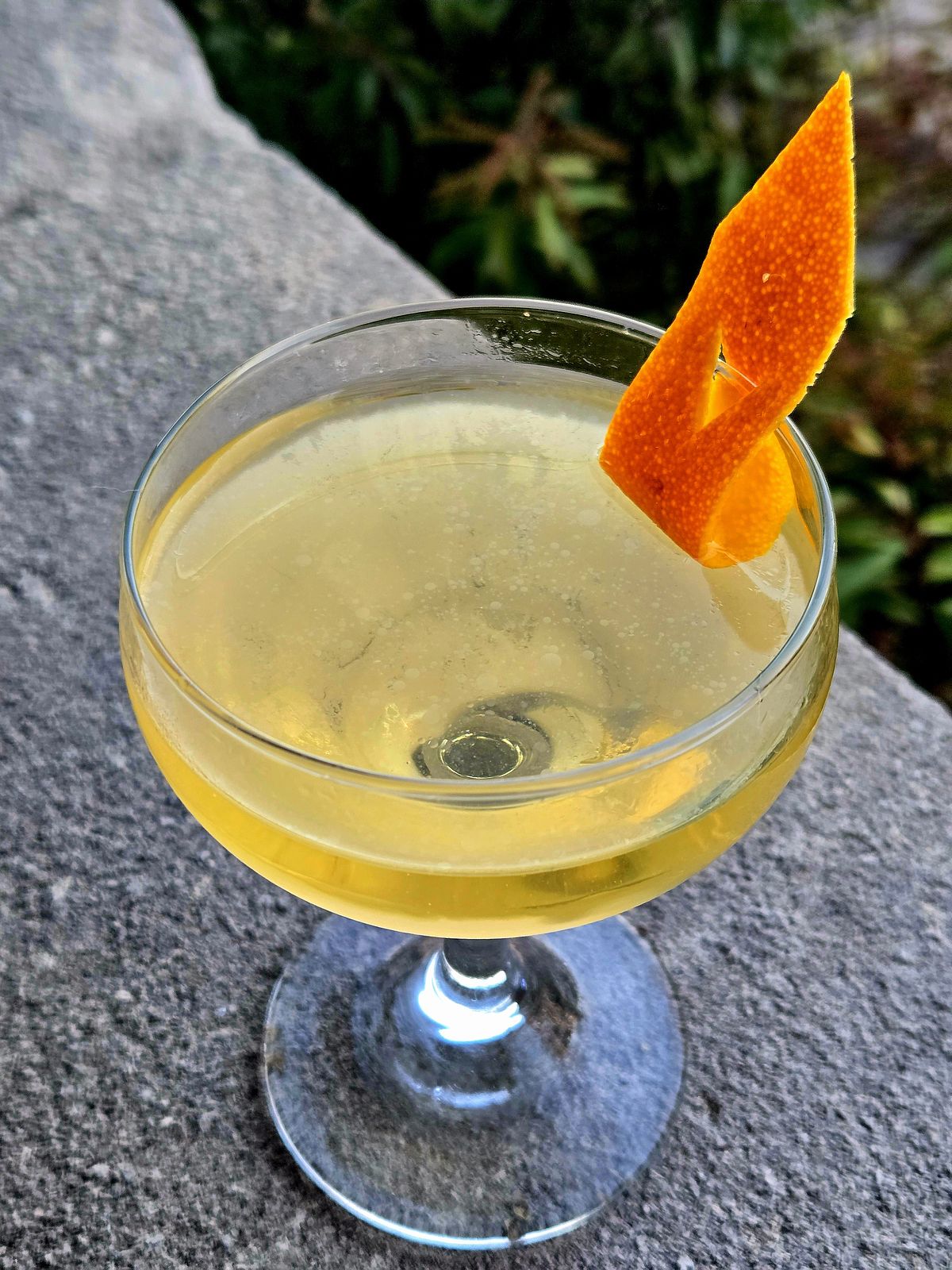 The Matador with orange flag garnish in a Coupe atop a stone wall.