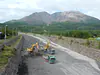 Japan, Kagoshima (2019): Debris being removed in a volcanic hazard mitigation canal near the active Sakurajima volcano (background)