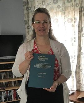 A woman standing in a room holding a blue book