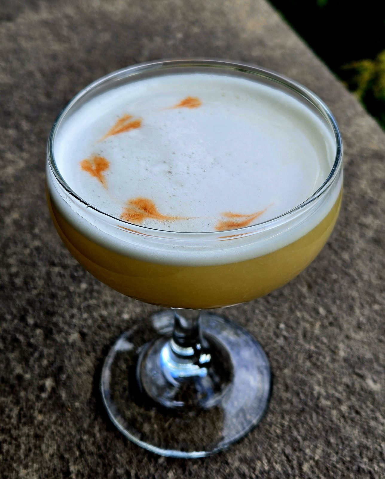 Sunset on the Charles in a Coupe with Angostura float garnish atop a stone wall.