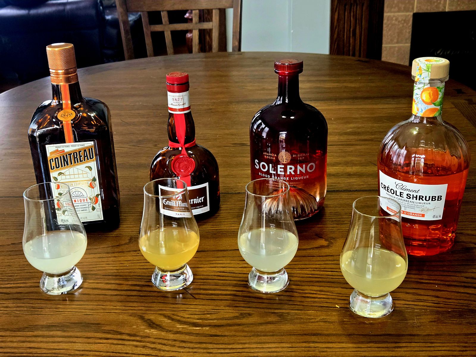 Coconut Margaritas made with four different orange liqueurs in Glencairn glass atop a wooden table.
