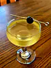 Orange Oracle in a coupe glass with Luxardo cherry garnish atop a wooden table