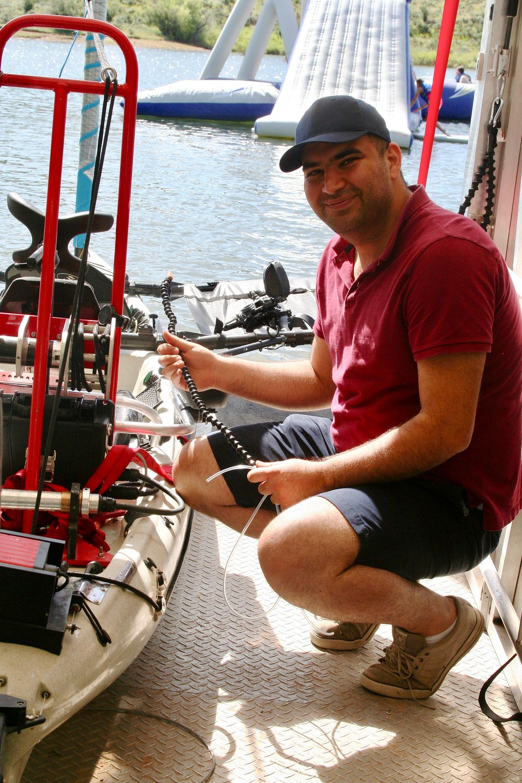 A man on a boat dock, crouching next to the boat with sip and puff tubing in his hand