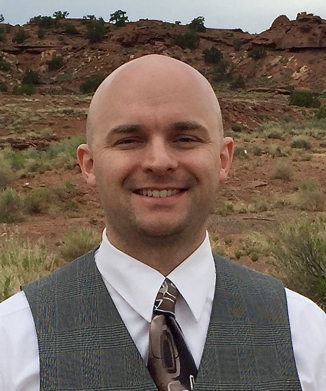 A headshot of Jordan Pyper with desert in the background.