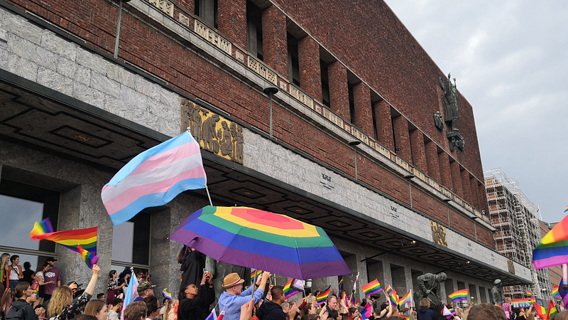 People gathering with Pride flags at Oslo City Hall. Photograph by Nathaniël Kunkeler.