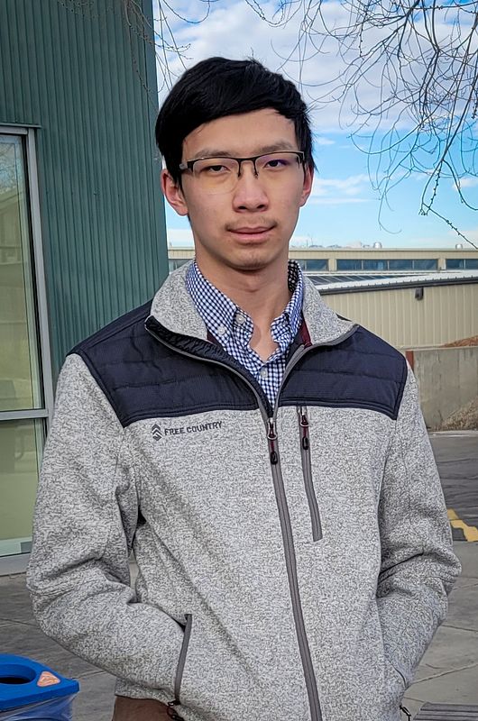 An image of Calvin Tu,  outside with buildings in the background.