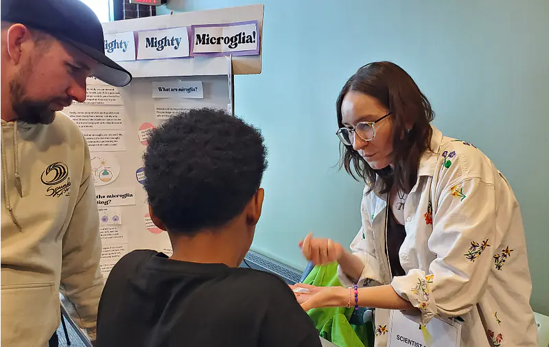 Guiding a student through Mighty, Mighty, Microglia! an interactive activity developed in the Science Communication Fellows Program at a Scientist Spotlight Event.